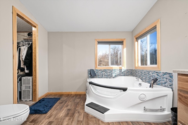 bathroom featuring a bath, wood-type flooring, and toilet