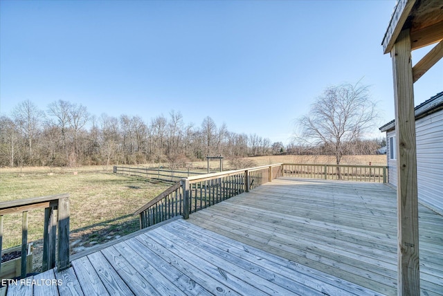 wooden deck with a rural view and a lawn