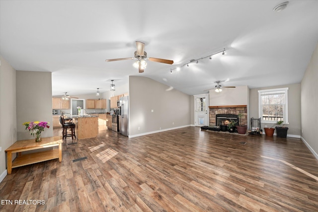 living room with a stone fireplace, vaulted ceiling, dark hardwood / wood-style floors, and ceiling fan