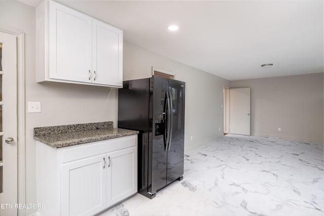 kitchen with dark stone countertops, black refrigerator with ice dispenser, and white cabinets