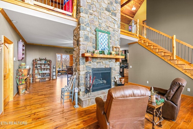 living room featuring hardwood / wood-style flooring, a towering ceiling, ornamental molding, and a fireplace