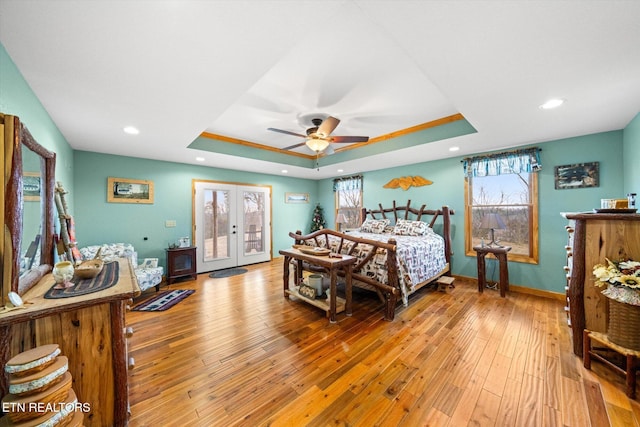 bedroom with french doors, access to outside, light hardwood / wood-style floors, and a tray ceiling