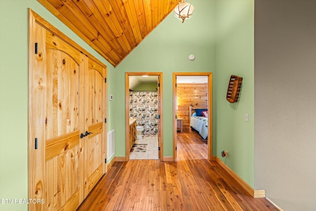 hall with lofted ceiling, wood-type flooring, and wooden ceiling