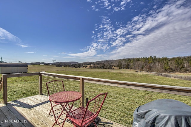 deck with a rural view, grilling area, and a lawn