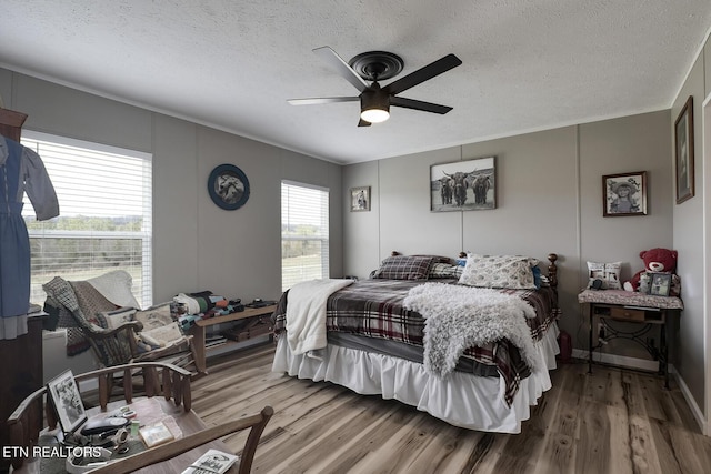 bedroom featuring ceiling fan, hardwood / wood-style flooring, and a textured ceiling