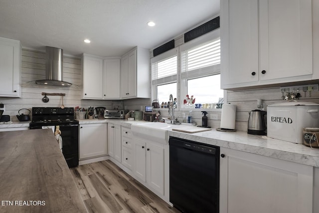 kitchen with white cabinetry, sink, backsplash, black appliances, and wall chimney range hood