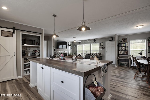 kitchen featuring white cabinetry, decorative light fixtures, dark hardwood / wood-style floors, a kitchen island, and a barn door