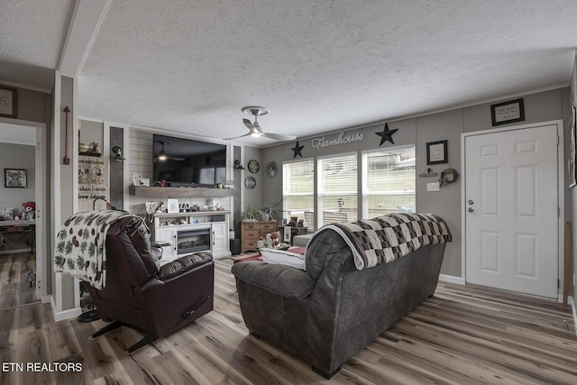 living room with ceiling fan, ornamental molding, hardwood / wood-style floors, and a textured ceiling