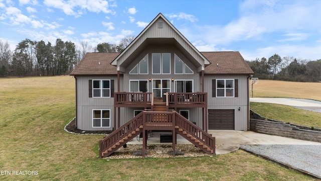 rear view of property featuring a garage, a deck, and a lawn