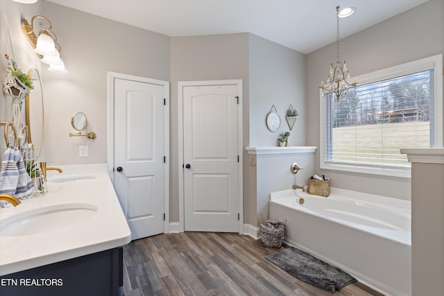 bathroom featuring a bathing tub, hardwood / wood-style floors, vanity, and an inviting chandelier