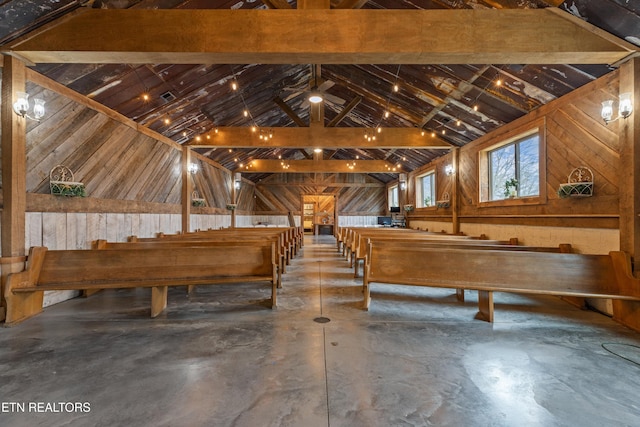 interior space with vaulted ceiling, concrete flooring, and wood walls