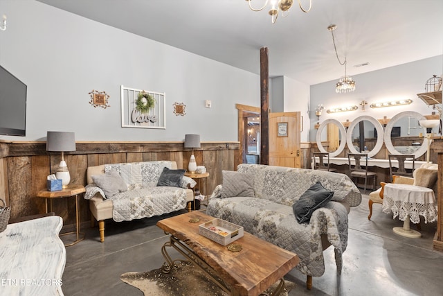 living room with an inviting chandelier and wood walls