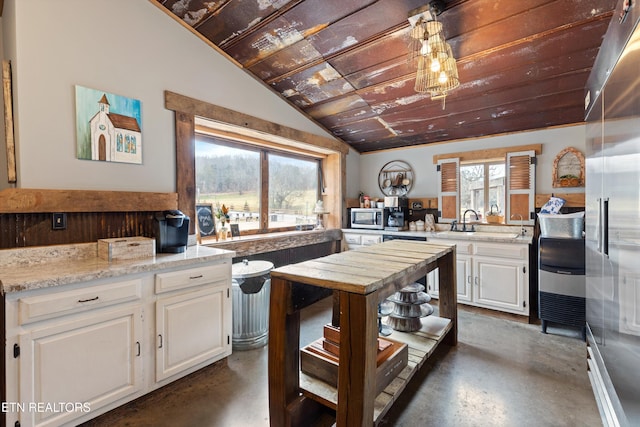 kitchen with lofted ceiling, sink, white cabinetry, stainless steel appliances, and light stone counters