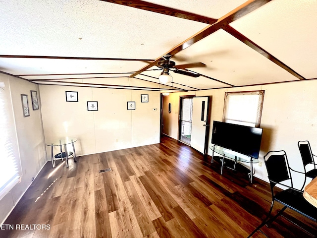 unfurnished living room with hardwood / wood-style flooring, ceiling fan, a textured ceiling, and vaulted ceiling with beams