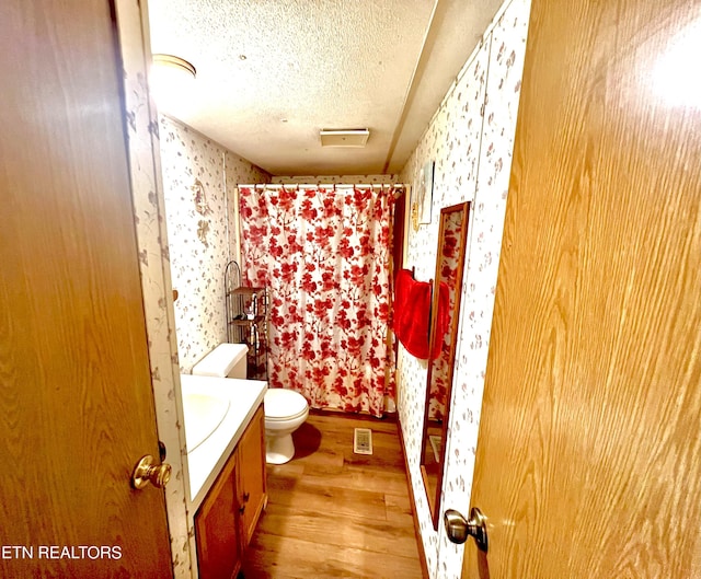 bathroom with toilet, a shower with curtain, a textured ceiling, vanity, and hardwood / wood-style flooring