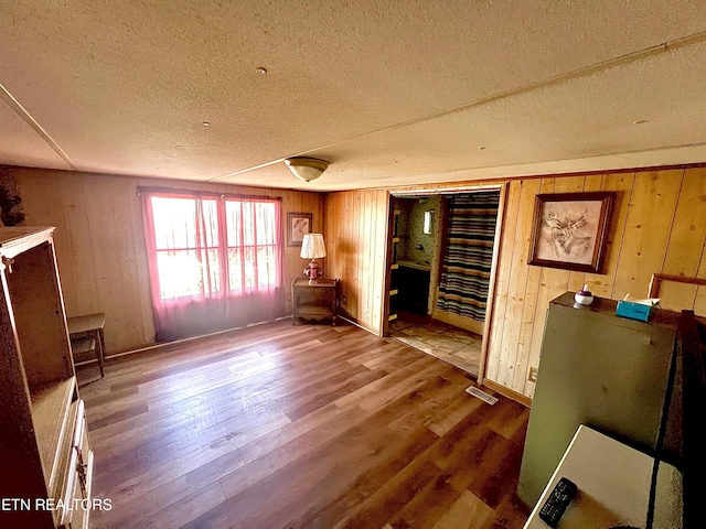 interior space with wood-type flooring, a textured ceiling, and wooden walls