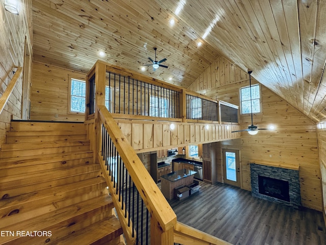 stairway with a fireplace, wood ceiling, wooden walls, and high vaulted ceiling