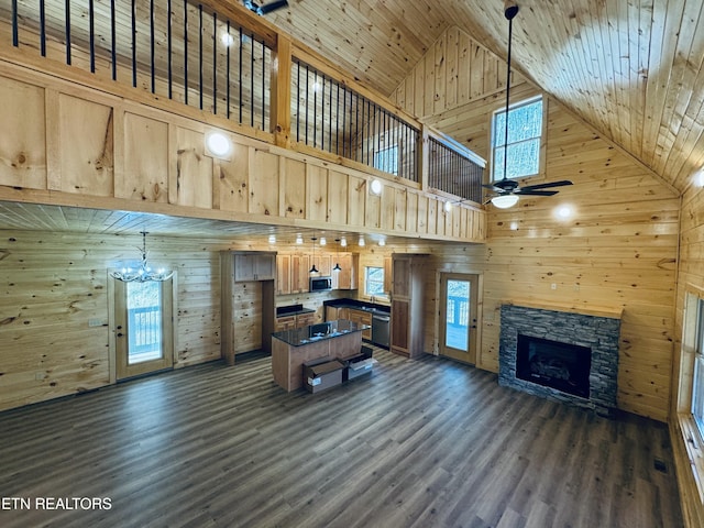 living room featuring wood ceiling, a fireplace, ceiling fan with notable chandelier, and wood walls