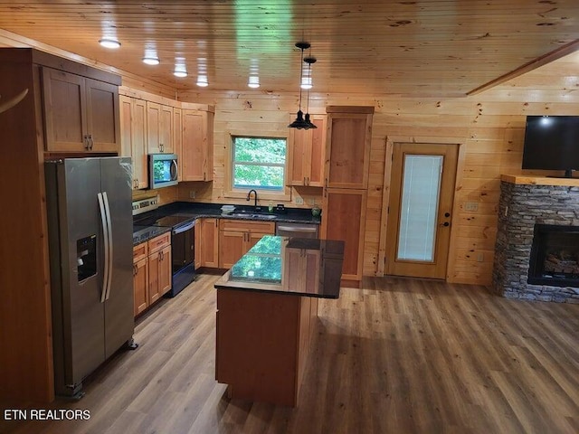 kitchen featuring pendant lighting, sink, appliances with stainless steel finishes, a center island, and a fireplace