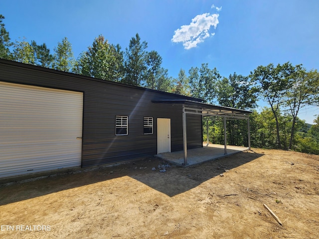 rear view of house featuring a carport, a garage, and an outdoor structure