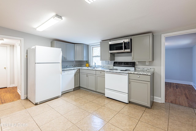 kitchen featuring light tile patterned flooring, white appliances, and gray cabinetry