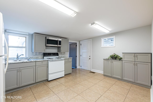 kitchen featuring sink, white appliances, gray cabinetry, plenty of natural light, and light stone counters