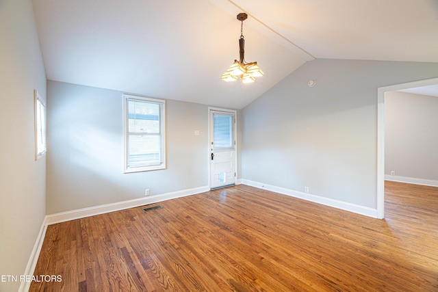 empty room with wood-type flooring and vaulted ceiling