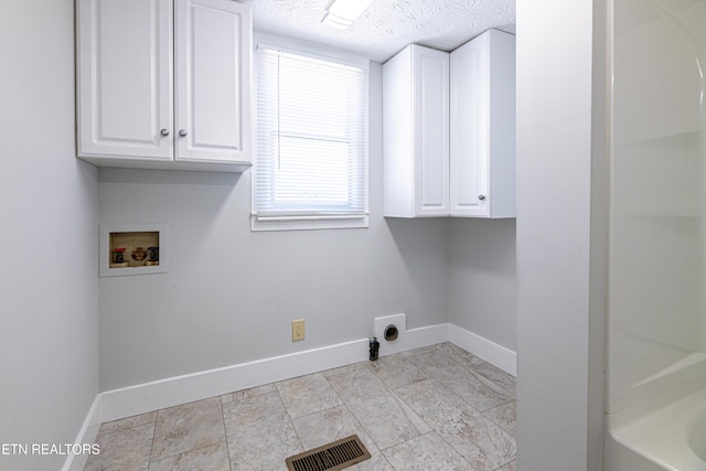 clothes washing area featuring cabinets, hookup for an electric dryer, hookup for a washing machine, and a textured ceiling