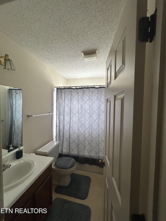 bathroom with vanity, toilet, and a textured ceiling