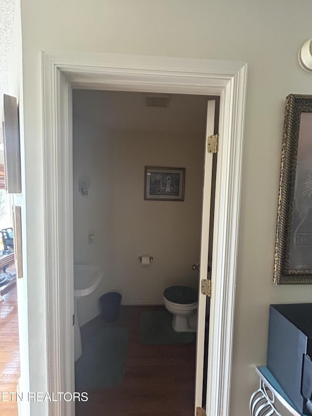 bathroom with hardwood / wood-style flooring and toilet