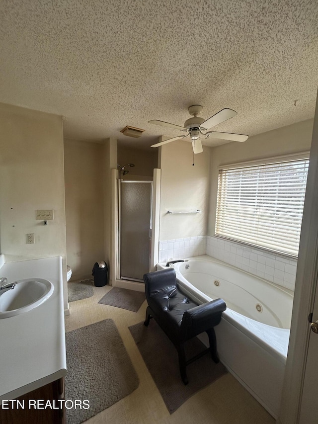 bathroom featuring vanity, ceiling fan, plus walk in shower, and a textured ceiling