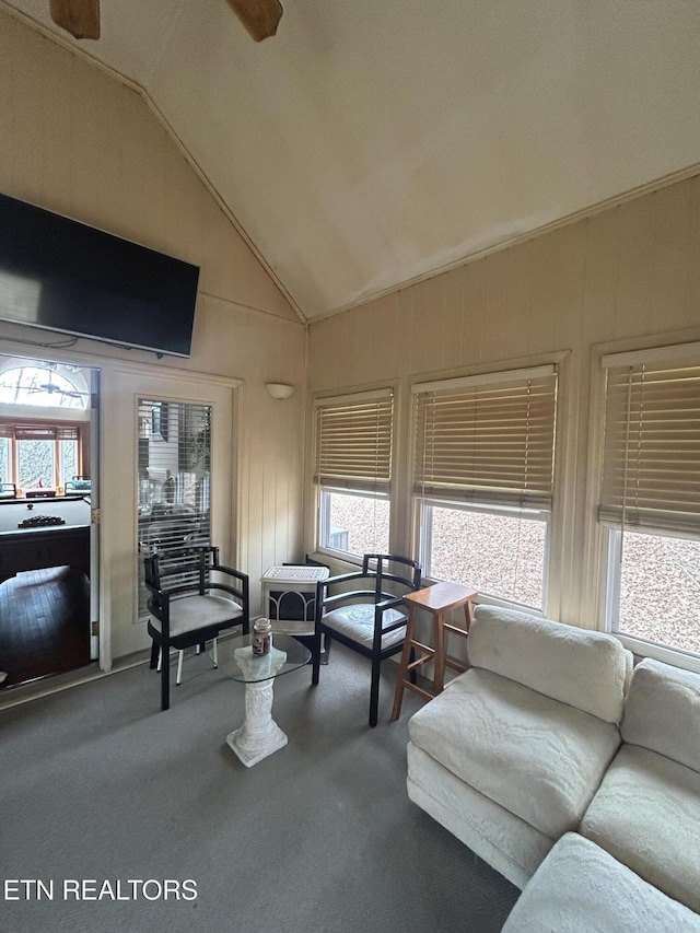 living room with lofted ceiling, wooden walls, and carpet flooring