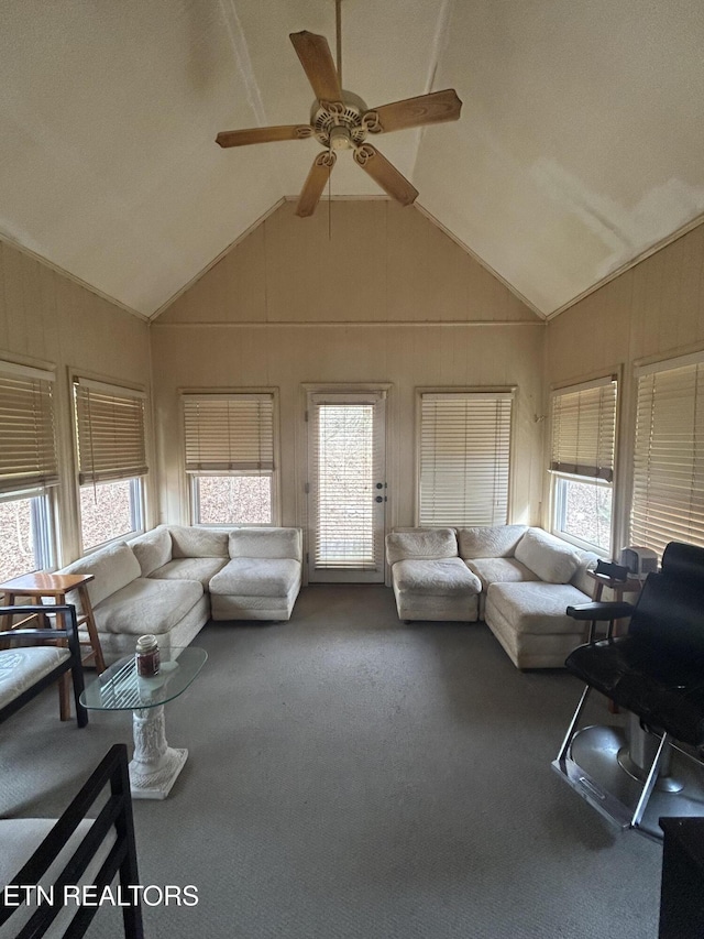 unfurnished living room with lofted ceiling, carpet floors, ceiling fan, and wood walls