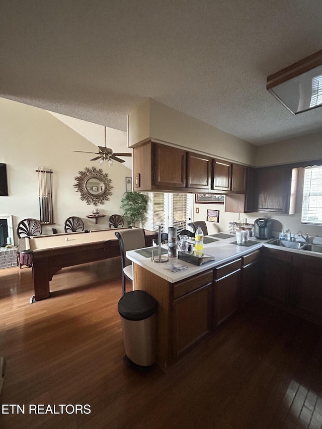 kitchen featuring dark wood-type flooring, dark brown cabinetry, sink, kitchen peninsula, and ceiling fan