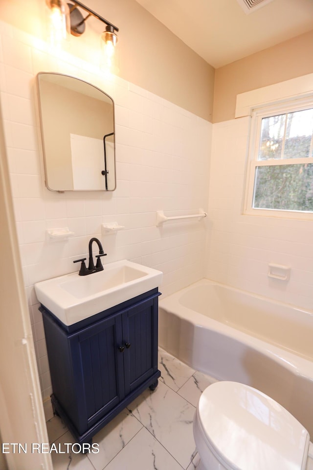 full bathroom with vanity, tile walls, washtub / shower combination, and toilet