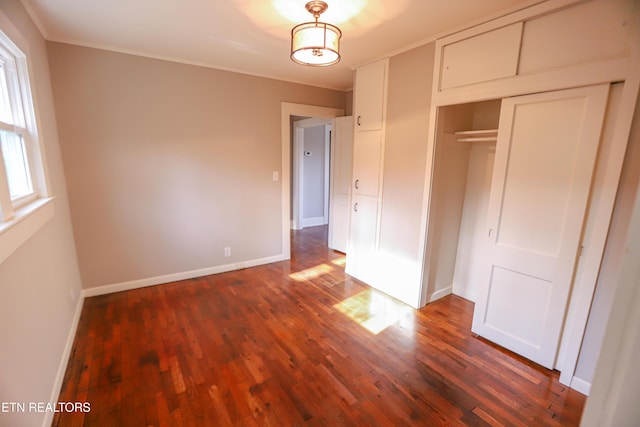 unfurnished bedroom featuring a closet, crown molding, and dark hardwood / wood-style floors