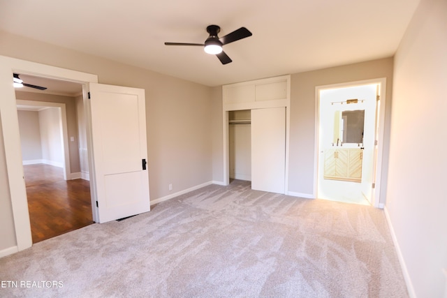 unfurnished bedroom featuring connected bathroom, light colored carpet, a closet, and ceiling fan