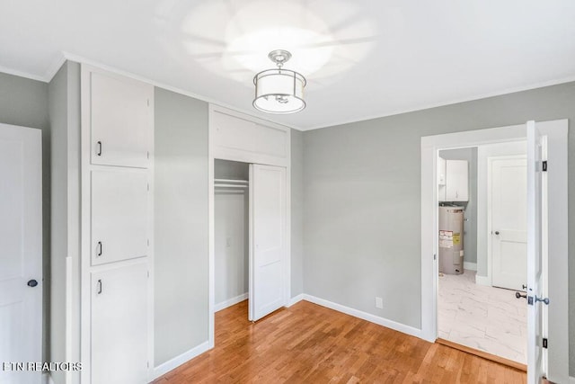 unfurnished bedroom featuring crown molding, wood-type flooring, electric water heater, and a closet