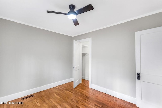 unfurnished bedroom with ceiling fan, ornamental molding, a closet, and wood-type flooring