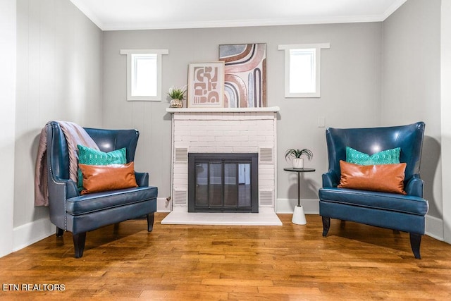 sitting room with crown molding, wood-type flooring, and a fireplace