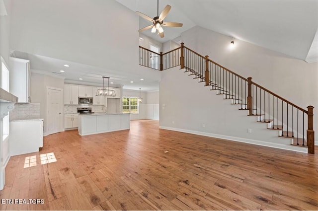 295 Caulderwood Ln, Lenoir City, TN 37771 - unfurnished living room featuring stairs, light wood-type flooring, high vaulted ceiling, ceiling fan with notable chandelier, and a sink