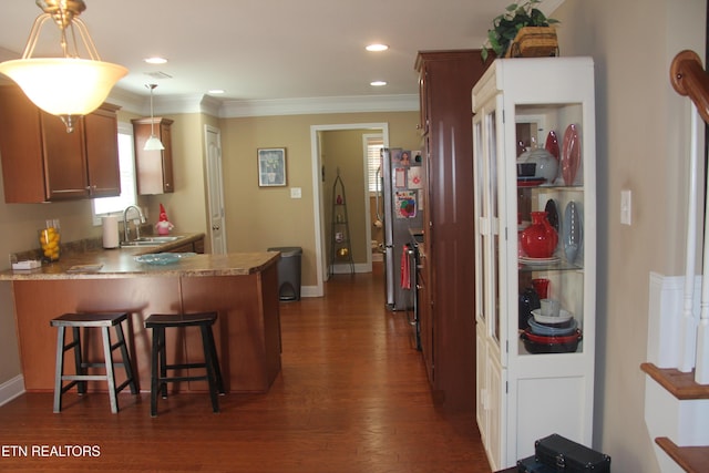 kitchen with dark hardwood / wood-style floors, stainless steel refrigerator, decorative light fixtures, a kitchen breakfast bar, and kitchen peninsula