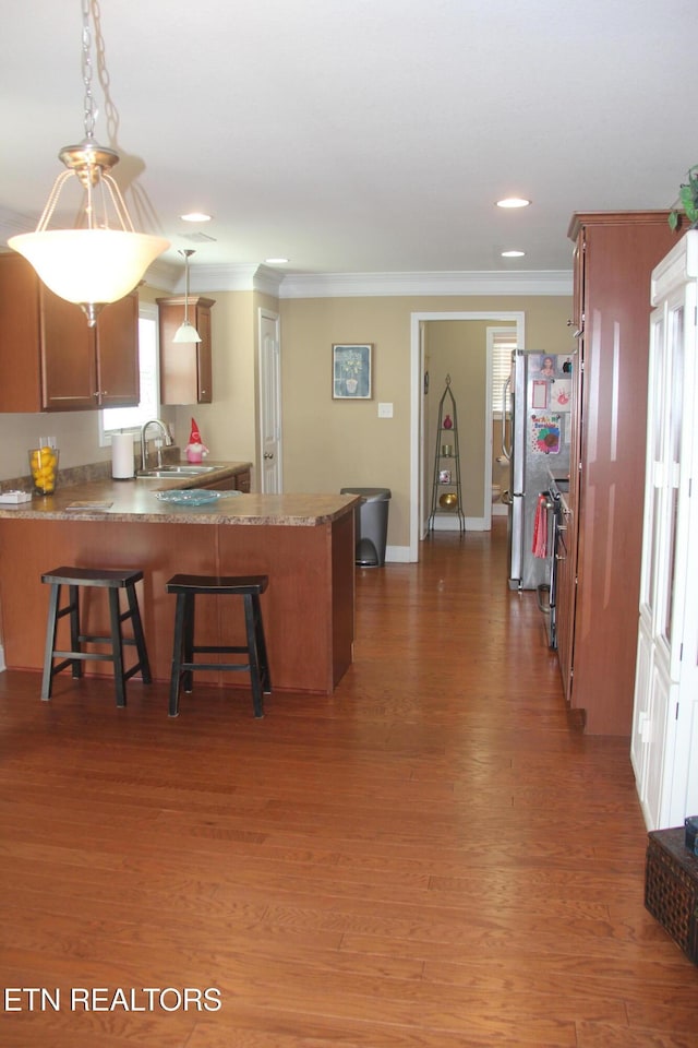 kitchen featuring sink, crown molding, dark hardwood / wood-style floors, kitchen peninsula, and pendant lighting