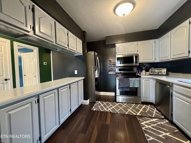 kitchen with a textured ceiling, stainless steel appliances, dark hardwood / wood-style floors, and white cabinets