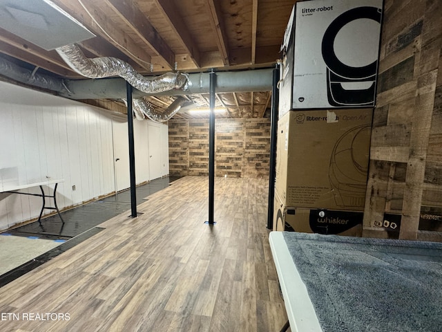 basement featuring wood-type flooring and wooden walls