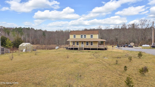 view of front of property with a wooden deck, an outdoor structure, and a front lawn