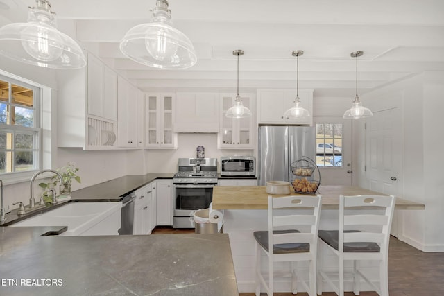 kitchen with white cabinetry, sink, stainless steel appliances, and a kitchen breakfast bar