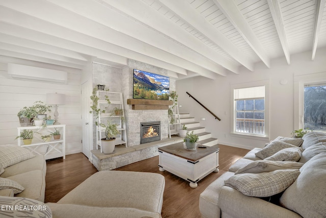 living room featuring beamed ceiling, a fireplace, dark wood-type flooring, and a wall unit AC