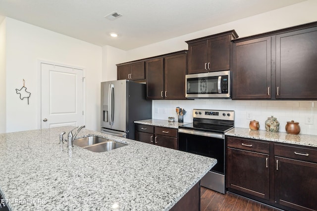 kitchen with light stone counters, sink, backsplash, and appliances with stainless steel finishes