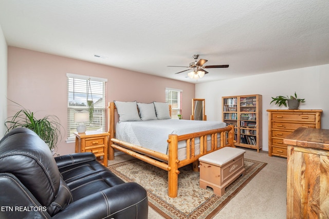 bedroom featuring ceiling fan, multiple windows, light carpet, and a textured ceiling